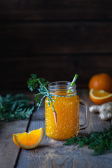 Healthy food. Carrots and carrot juice with orange ginger in a glass jar in a metal basket on a dark wooden background