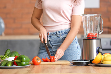 Young woman making smoothie in kitchen at home