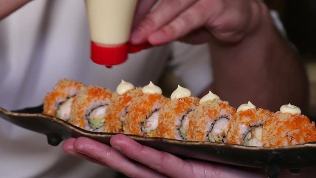 The cook finishes putting cheese on philadelphia roll