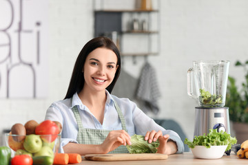Young woman making vegetable smoothie in kitchen at home