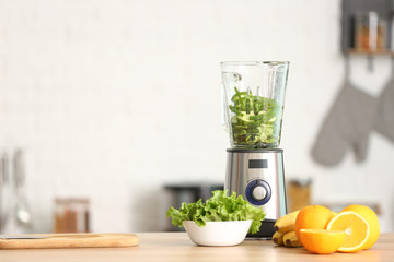 Modern blender with fresh fruits and vegetables on table in kitchen