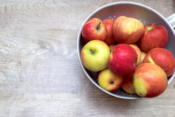 Ripe red apples in metallic bowl on wooden table with copy space for text. close up of fresh fruits concept, vitamin fruits background, banner