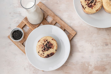 Delicious fresh vanilla muffin with sprinkled cocoa on a light background