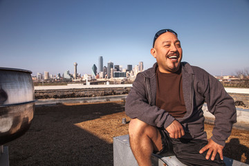 Laughing man sitting on rooftop, Dallas, Texas, USA