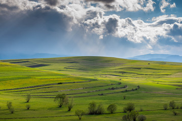 Beautiful green valley at springtime, gathering stormclouds , agricultural fields in Transylvania, Romania.