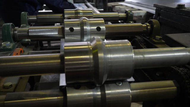 Metal rolling machine. A galvanized sheet of metal moves along the machine. Factory for the manufacture of metal products