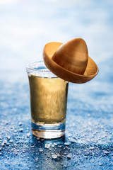 Gold tequila shot with a sombrero. One glass of tequila with salt