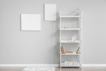 Rack with stylish decor near grey wall in room