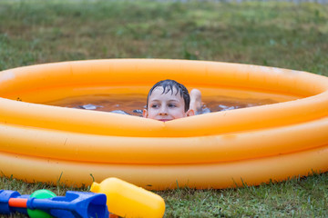 Chłopiec relaksujący się w dmuchanym basenie z wodą - obrazy, fototapety, plakaty
