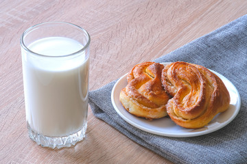 Milk in a glass on a background of burlap. Freshly baked sweet rolls on a saucer. Natural product. Isolated background. Milk drink. Splash of milk.