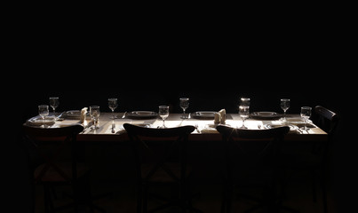Dining table served with plates, glasses, forks and knives. Without food. On a black background.