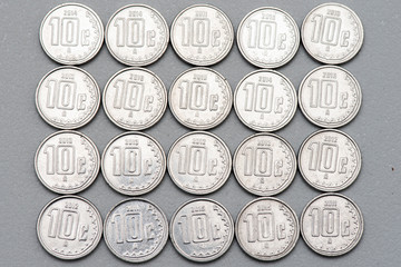 Monedas de 10 centavos acomodadas en linea sobre un fondo de color gris