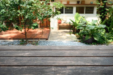 Fototapeta na wymiar Rustic brown wooden table top on blurred green plant in garden backyard