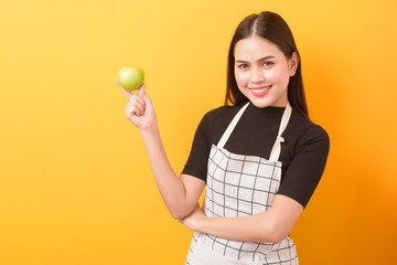 Beautiful woman is holding apple on yellow background