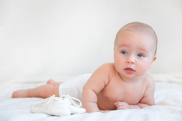 Beautiful baby playing with legs in white bedroom on white background