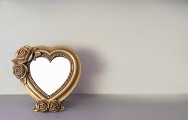 Mock up of gold heart shaped picture frame on modern counter.