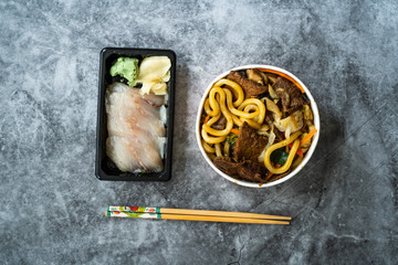 Take Away Asian Food Menu Set with Beef Udon Noodle Soup and Raw Suzuki Fish Sashimi served with Pickled Ginger and Wasabi.