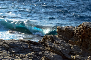 Fototapeta premium Cliffs at the Aegean sea in Ikaria with blue waves breaking on the shore, Greece