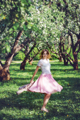 Obraz na płótnie Canvas A girl in a light pink skirt runs through a blossoming apple orchard