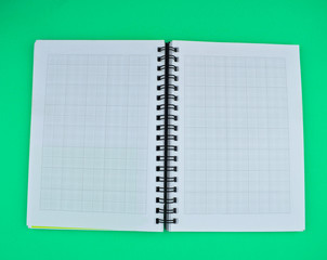 Top view of an open white spiral paper notebook placed on top of a paper background