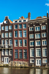 Fototapeta premium Old traditional leaning houses along the canal in Amsterdam, Netherlands