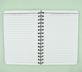 View of an open white spiral paper notebook placed on top of a paper background