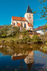 Fototapeta na wymiar Beautiful spring view with reflections of a church at Walchsing, Vils, Bavaria, Germany