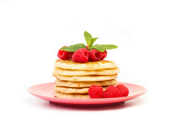 Tortitas con frambuesas frescas y naturales y hojas de menta sobre un plato rosa redondo sobre un fondo blanco aislado. Vista de frente. Copy space