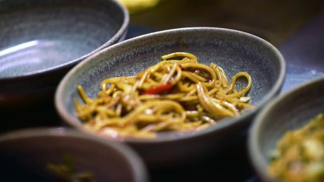 Yakisoba stir fry chicken noodles. Closeup of Modan-yaki food served in a rustic dish. Asian gourmet cuisine cooking background. Soft focus, motion blurred footage