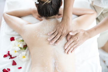 Obraz na płótnie Canvas Asian woman massaging spa with salt. Beauty therapist pouring salt scrub on woman back at health spa.