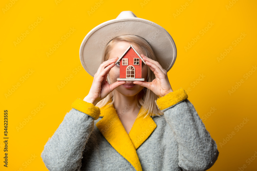 Sticker style blonde woman in hat and coat with toy house