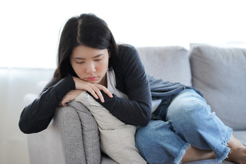 Depressed lonely unhappy mental woman sitting alone on the sofa at home with hand on face feel stress sad and worried disappointment while facing problem during coronavirus or covid-19 pandemic