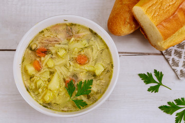Plate full of chicken noodle soup with bread.