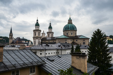 Fototapeta na wymiar Rooftops buildings cityscape and Roman Catholic Salzburg Cathedral (Dom zu Salzburg) at Residenzplatz square at rainy day