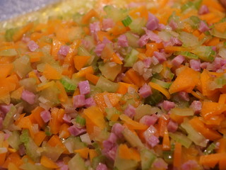 Klein geschnittene Zwiebeln, Karotten, Stangensellerie und Speckwürfel werden in einer Pfanne aus Edelstahl angebraten