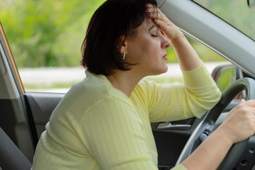 Stress and malaise of a woman driving a car. Fatigue on the road. Tired girl in traffic jam