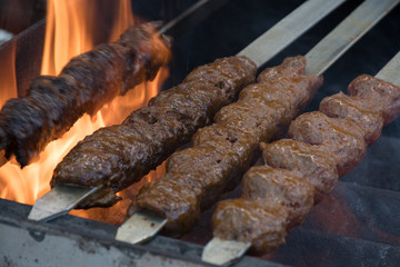Adana kebab (ground lamb minced meat on skewer on grill over charcoal).
