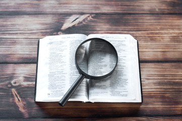 Open bible on a wooden table. Magnifier - Powered by Adobe