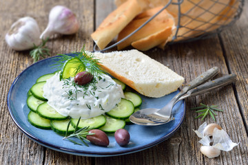 Typischer griechischer Tzatziki-Imbiss mit Gurken und Oliven auf blauem Keramikteller – Typical...