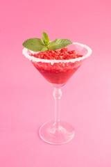 Frozen juice with strawberry in a one martini glass  on the pink background. Location vertical. Closeup.