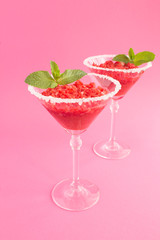 Frozen juice with strawberry in the two martini glasses  on the pink background. Location vertical. Closeup.