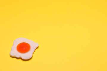 Jelly-fried eggs are shot close in the lower right corner against a bright yellow background. There is a place for text. An unusual photo was made for your colorful design.