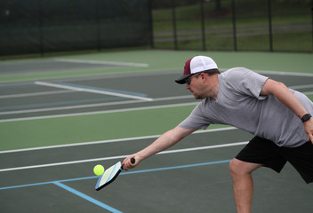 A man stretches for a shot during a pickleball match.