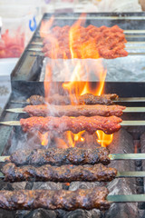 Adana kebab (ground lamb minced meat on skewer on grill over charcoal).
