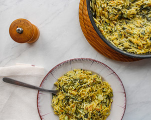 Orzo primavera with green veggies in vintage place over white marble table. One pot pasta with...