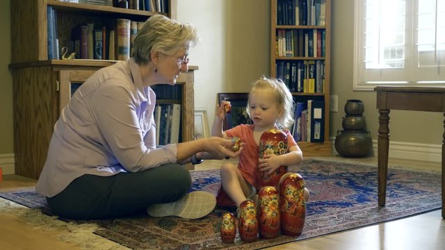 Grandmother playing with Russian nesting or matrushka dolls with toddler granddaughter