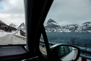 Lofoten islands, Norway. Cold fjord with snowy mountains. Photos taken on the road from the window of the car