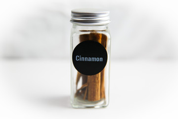 Cinnamon spice jar with cinnamon sticks on white background
