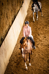 Teenage girl horseback riding in sport hall