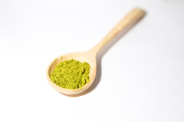 Green powder of Japanese matcha tea in a teaspoon. Matcha on a white background, isolated